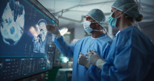 Caucasian Male and Female Surgeons Analyze Brain Scans on a Digital Monitor, Planning Surgical Strategy in a High-tech Operating Room. Colleagues Working Together, Preparing for Surgery Diseñan con inteligencia artificial una molécula con potencial para tratar el alzhéimer y el cáncer